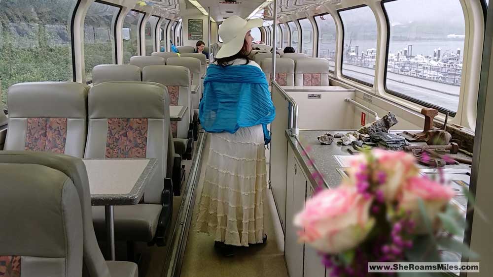 A Woman In A White Hat And Blue Scarf Standing On A Train